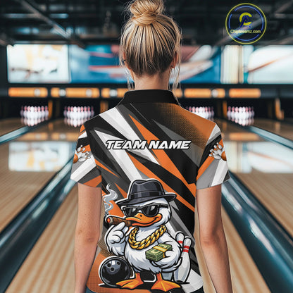 Back view of a female model in a black and orange bowling polo shirt at a bowling lane featuring a duck-themed bowling graphic with pins and ball.