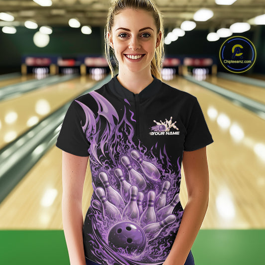 Female model in a bowling lane wearing a black and purple quarter zip shirt featuring a flaming bowling ball crashing into bowling pins with fiery design.