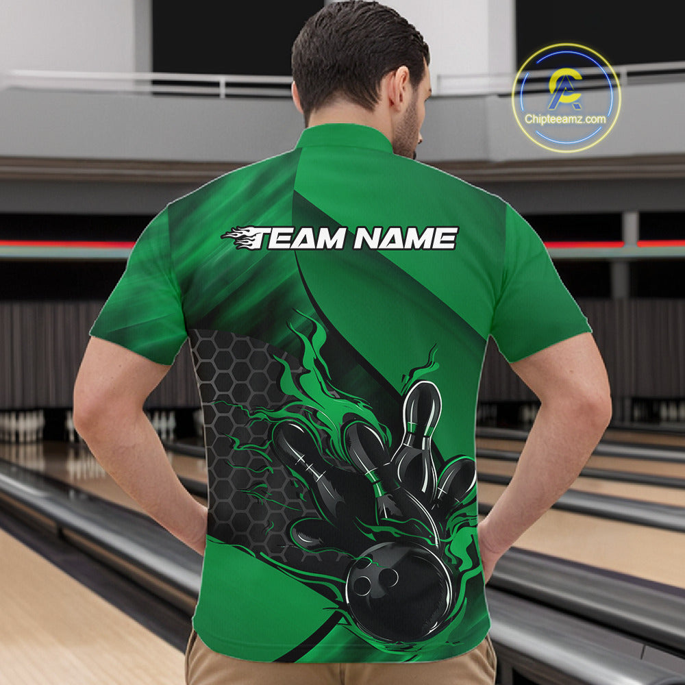Front view of a male model in a bowling alley wearing a black and green quarter-zip shirt featuring a flaming bowling ball hitting the pins.