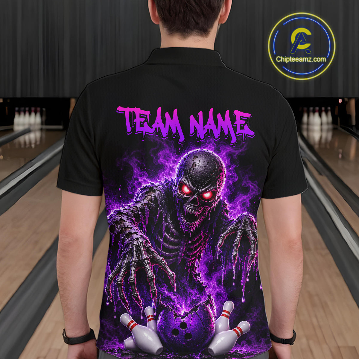 A man viewed from behind wearing a black short-sleeve polo shirt with a large graphic print of a glowing purple skull monster and the text 'TEAM NAME' on the back. Bowling lanes are visible in the background, and a circular 'Chipteeamz.