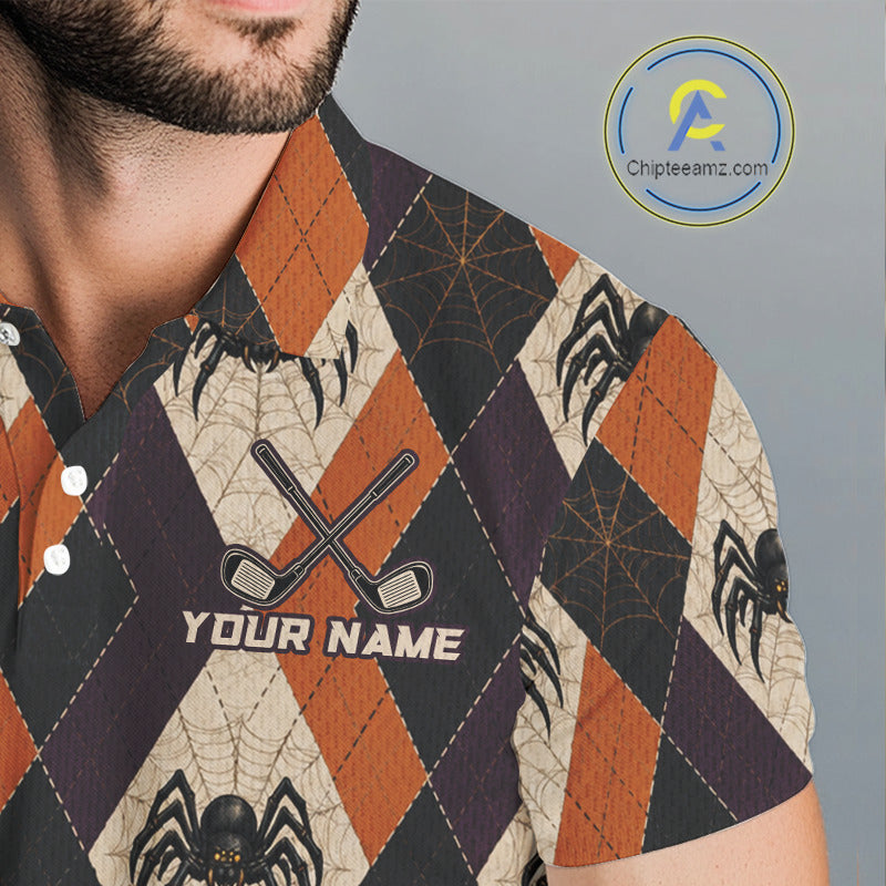 A close-up of a man wearing a short-sleeve collared shirt with a Halloween-themed argyle pattern featuring orange, dark purple, and beige diamonds with spiderweb motifs, black spiders, and a custom text placeholder 'YOUR NAME' on the chest.