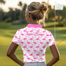 Load image into Gallery viewer, Woman wearing a white polo shirt with pink flamingo pattern and 'Team Name' text on the back, standing on a golf course.